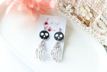 Load image into Gallery viewer, Tiny Skull Head & Steel Skeletal Hand Dangle Earrings – Handmade Gothic Halloween Jewelry | Polymer Clay Skull Earrings | KeandKi Designs